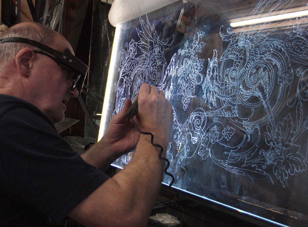 Artist making markup on the glass with a diamond bur before engraving